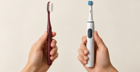 Two hands holding an electric toothbrush and a manual toothbrush for comparison
